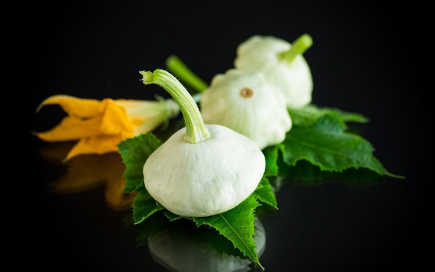 Courge bio fraîche avec fleurs et feuillage isolé sur fond noir