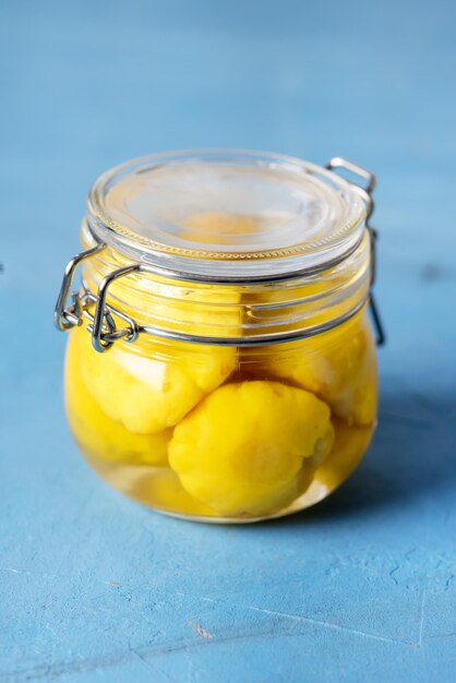 Courge jaune marinée dans un bocal en verre sur fond bleu