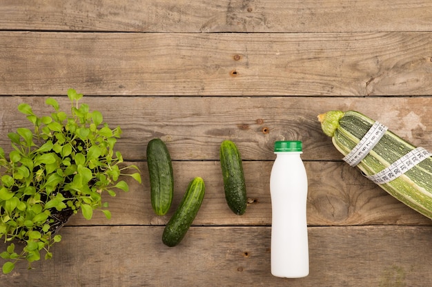 Courge à moelle ruban à mesurer bouteille d'eau et de concombres sur une table en bois marron