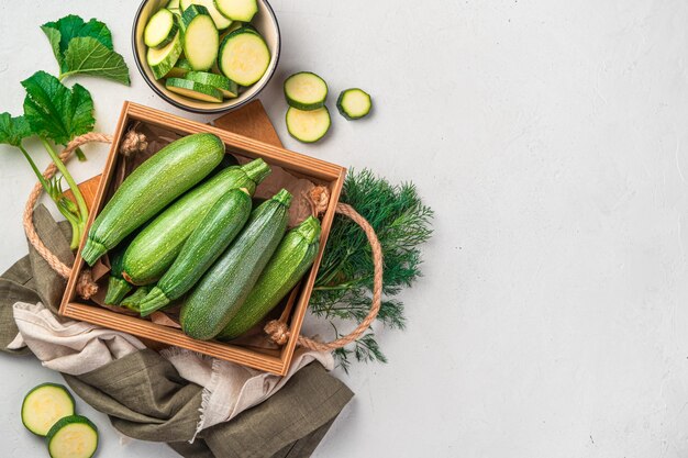 Courgettes entières et tranchées sur fond gris avec un espace pour la copie. Vue de dessus. Alimentation naturelle et saine.