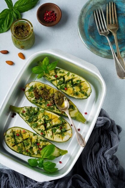 Courgettes épicées grillées avec sauce au poivre et pesto sous forme d'aluminium sur fond de béton gris. Contexte sélectif.