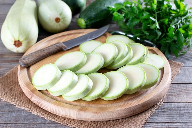 Courgettes fraîches entières et tranchées sur table en bois. Ingrédient végétarien sain