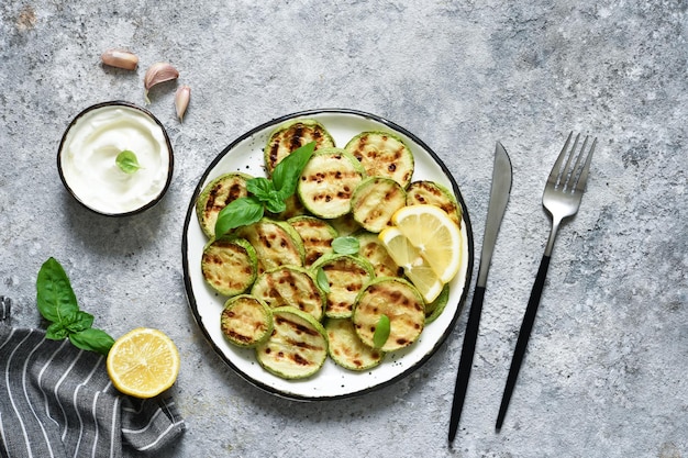 Courgettes grillées avec sauce sur fond de béton. Vue d'en-haut.