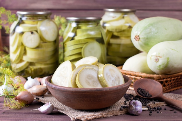 Courgettes marinées dans un bocal en verre sur une table en bois marron