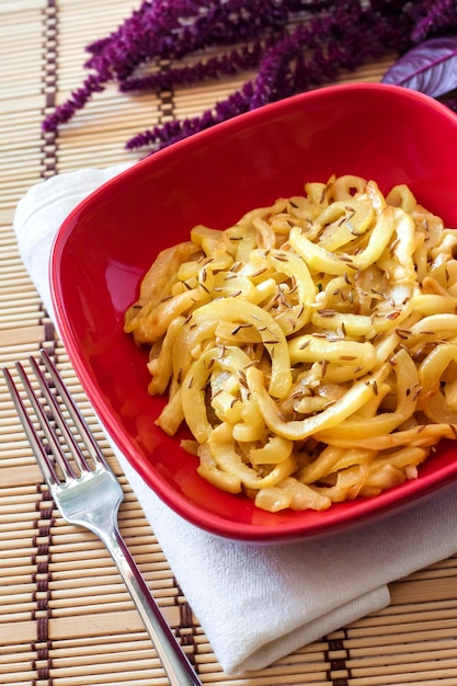 Courgettes mûres frites avec graines de cumin dans un bol carré rouge avec inflorescence Amarant en arrière-plan