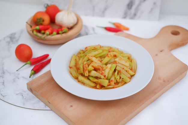 Des courgettes tranchées sur une assiette blanche avec du piment rouge