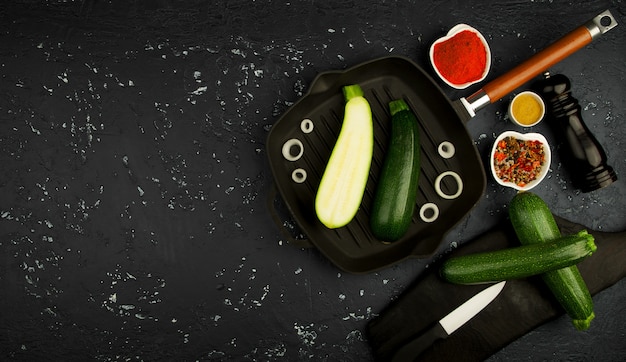 Courgettes vertes fraîches dans une casserole sur une table sombre. La vue du haut. Espace de copie.