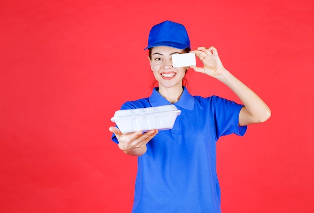 Courier Femme tenant une boîte à emporter blanche et présentant sa carte de visite.