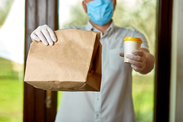 Courier, livreur en masque de protection et gants médicaux livre des plats à emporter, coronavirus