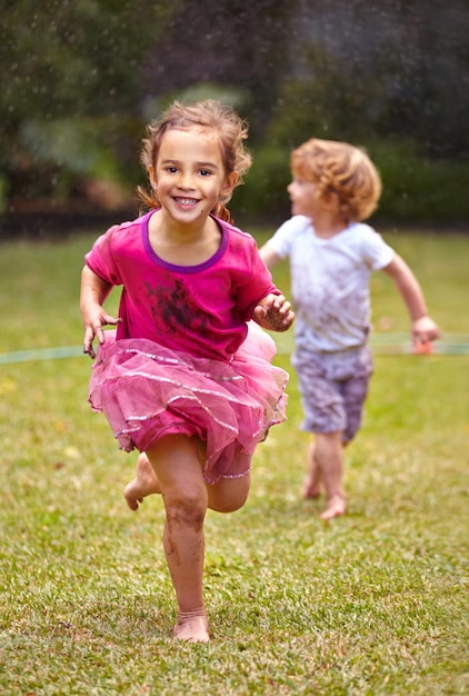 Courir aussi vite que possible Photo d'une petite fille courant avec son petit frère à l'extérieur