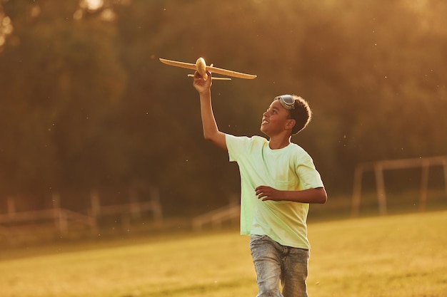 Courir avec un avion jouet Un enfant afro-américain s'amuse sur le terrain pendant la journée d'été