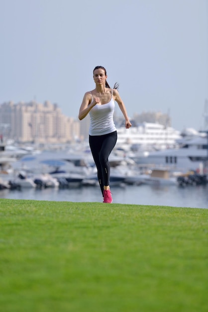 Courir dans le parc de la ville. Femme coureuse à l'extérieur du jogging le matin avec la scène urbaine de Dubaï en arrière-plan