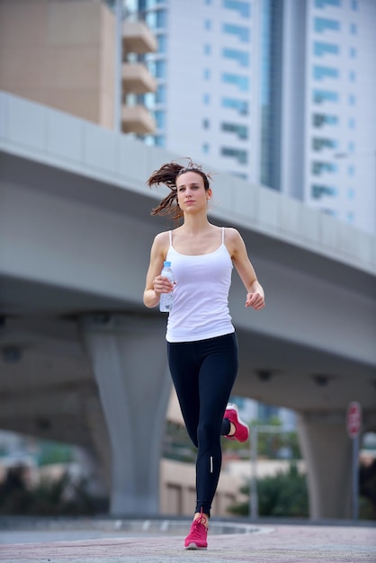 Courir dans le parc de la ville. Femme coureuse à l'extérieur du jogging le matin avec la scène urbaine de Dubaï en arrière-plan