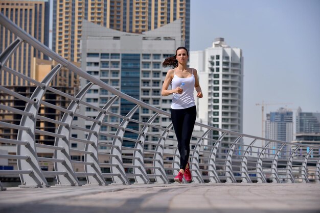 Courir dans le parc de la ville. Femme coureuse à l'extérieur du jogging le matin avec la scène urbaine de Dubaï en arrière-plan