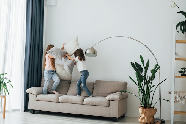 Courir avec des oreillers Enfants s'amusant dans la chambre domestique pendant la journée ensemble