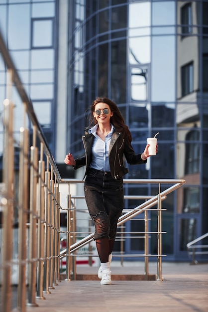 Courir vers la caméra. Jeune belle fille dans des vêtements chauds se promène dans la ville à son heure du week-end