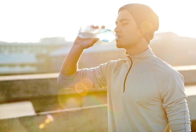 Courir vite boire profondément Photo d'un jeune homme jogger buvant de l'eau pendant une course dans la ville