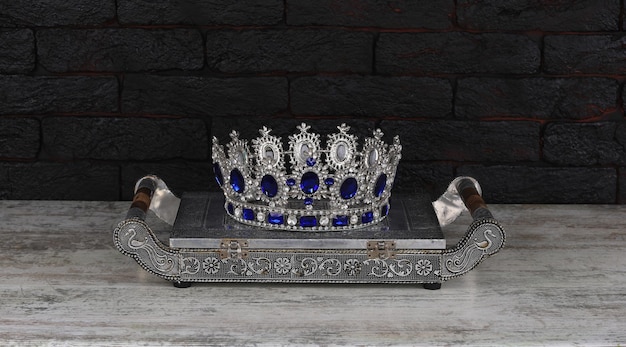 Une couronne d'argent avec des pierres bleues est posée sur une table.