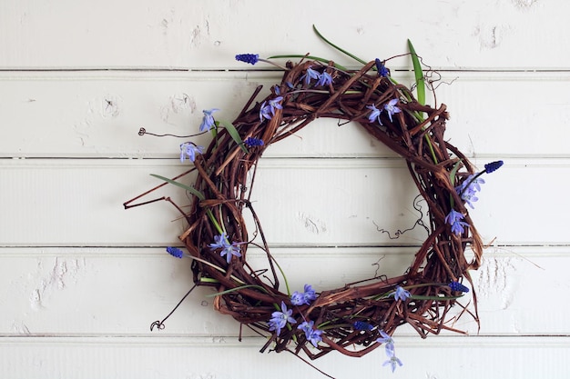 Une couronne de branches de raisins et les fleurs de printemps sur un fond de bois