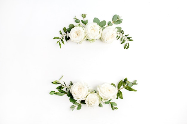 Couronne de cadre floral de boutons de fleurs roses blanches et d'eucalyptus sur fond blanc. Mise à plat, vue de dessus