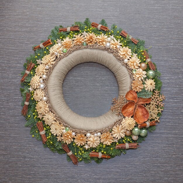 Couronne de décoration de Noël avec des cônes et des jouets de Noël sur fond gris. Vue de face