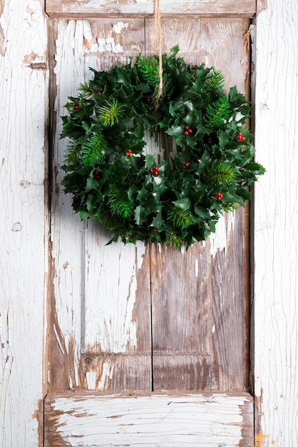 Couronne de décoration de Noël de feuilles vertes et baies houx ilex plante contre les vieilles portes en bois