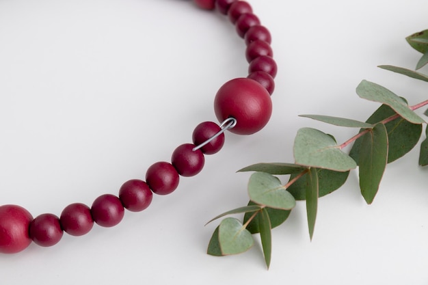 Couronne décorative faite de perles de couleur rouge et d'eucalyptus sur le tableau blanc Gros plan