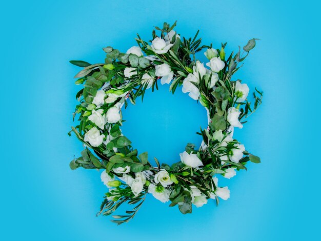 Couronne décorée de roses blanches sur fond bleu. Décoré. Vue ci-dessus