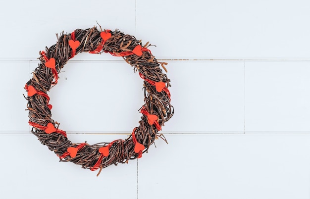 Une couronne faite de branches décorées de coeurs en bois sur un fond en bois blanc