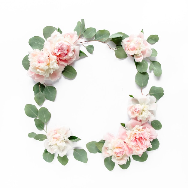 Photo couronne florale à cadre rond composée de pivoines roses et beiges, boutons floraux, branches et feuilles d'eucalyptus isolées sur fond blanc, vue de dessus plate