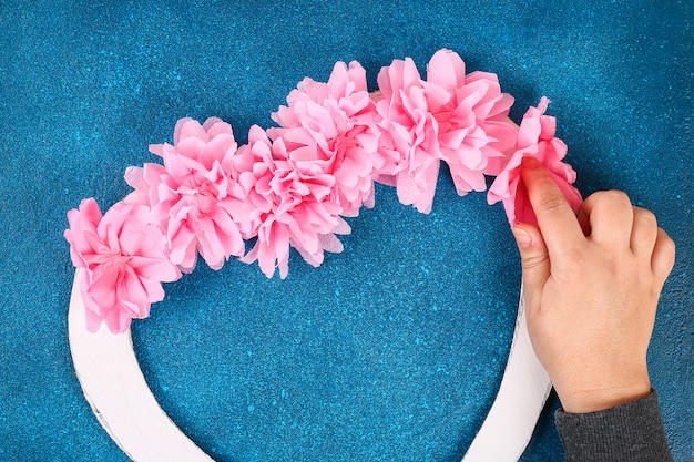 Photo couronne en forme de coeur décoré de fleurs artificielles fait des serviettes en papier de soie rose