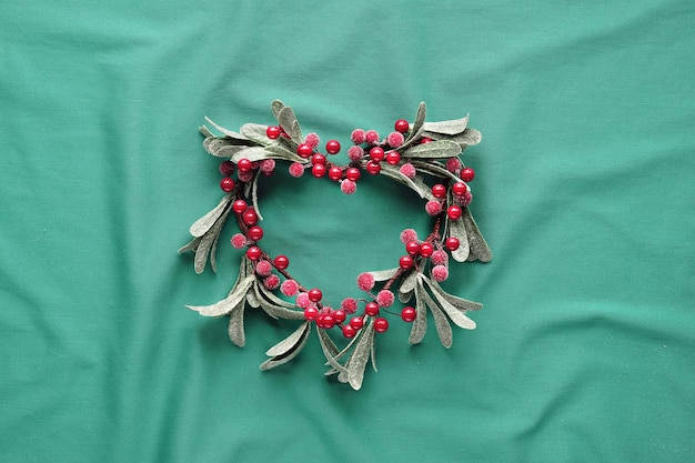 Photo couronne de gui décorative avec des feuilles givrées et des baies rouges en forme de coeur d'en haut à plat