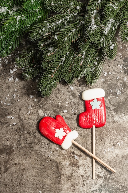 Couronne de joyeux Noël faite de branches de sapin et de sucettes sur fond de béton de pierre. Vacances de Noël et du Nouvel An, lumière dure moderne, ombre sombre. Neige artificielle, mise à plat, vue de dessus