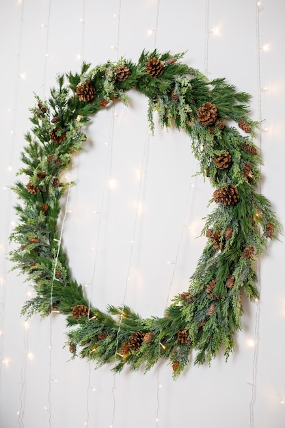 Couronne de Noël avec des branches d'un arbre de Noël accroché au mur. Déco du nouvel an dans une maison cosy