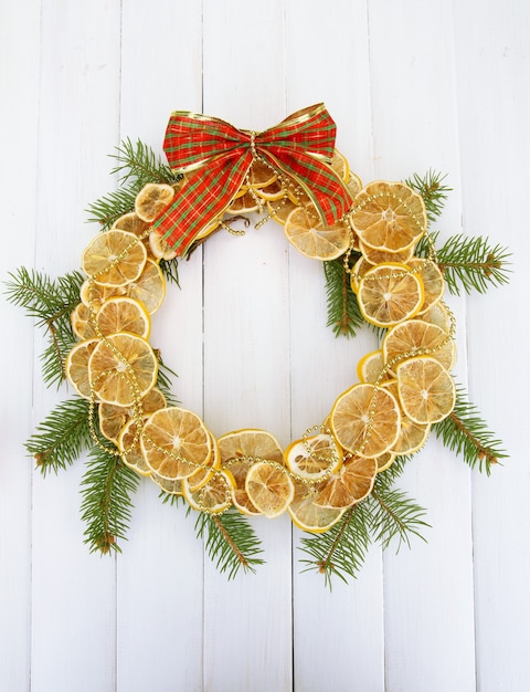 Couronne de Noël de citrons séchés avec sapin et archet, sur fond de bois blanc