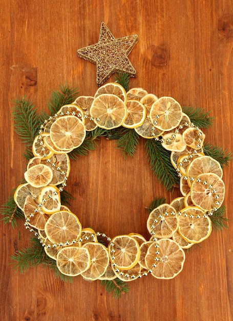 Couronne de Noël de citrons séchés avec sapin et étoile sur fond de bois