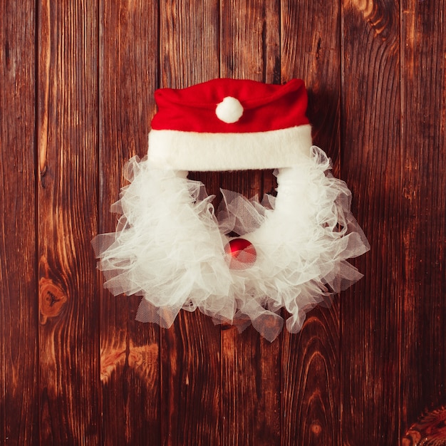 Couronne de Noël comme tête de Père Noël en dentelle et boule rouge sur la porte en bois