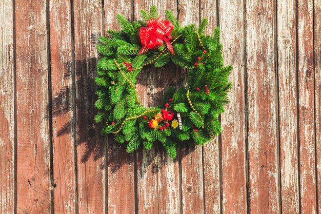 Couronne de Noël avec des décorations sur la porte en bois minable.