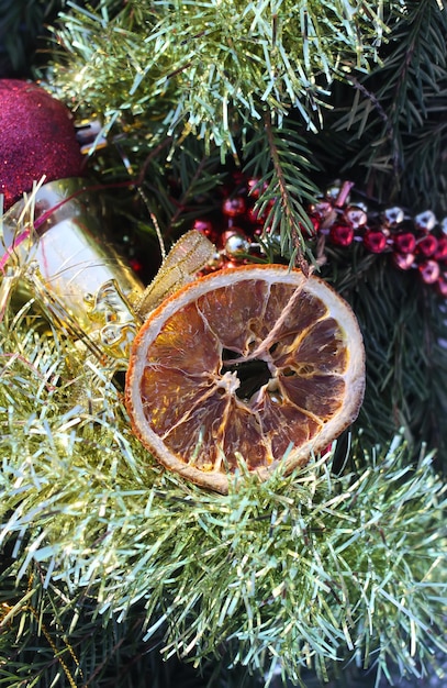 Couronne de Noël décorée de tranches d'orange sèches et de boules colorées sur fond de neige blanche.