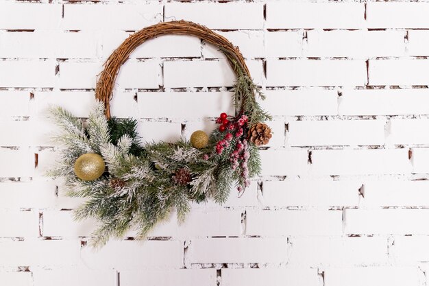 Une couronne de noël lumineuse traditionnelle suspendue au-dessus de la cheminée sur un mur de briques blanchesconcept de noël decorroom de nouvel an dans l'espace de copie de style loft