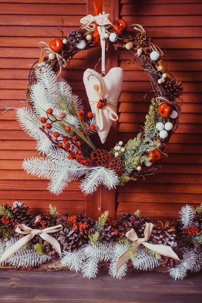 Couronne de Noël sur le mur en bois. Éléments rouges et blancs, coeur textile se bloque