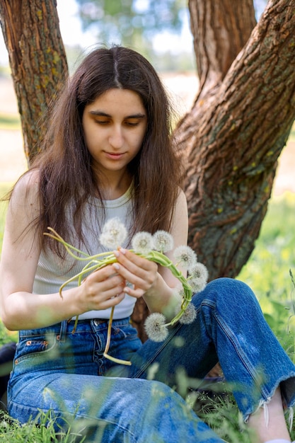 Photo une couronne de pissenlits blancs instructions étape par étape étape 3 une fille heureuse fait une couronne de poivrons blancs