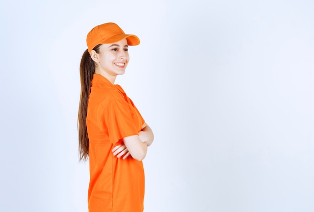 Photo courrier féminin portant un uniforme orange et une casquette croisant les bras et donnant un aspect professionnel