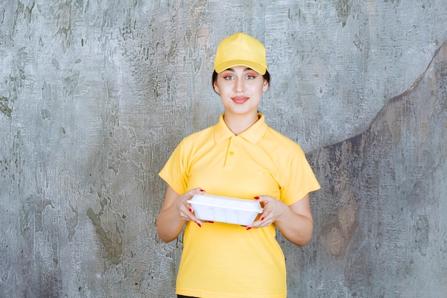 Courrier féminin en uniforme jaune livrant une boîte à emporter blanche