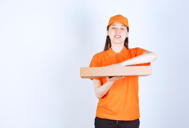 Courrier féminin en uniforme jaune tenant une boîte à emporter en carton.