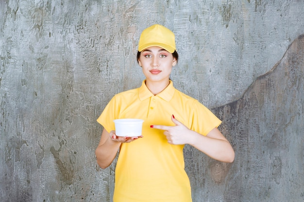 Courrier féminin en uniforme jaune tenant une tasse à emporter