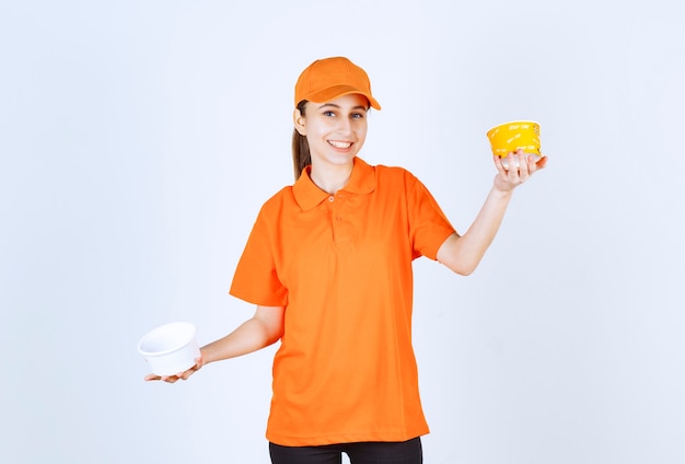 Courrier féminin en uniforme orange tenant une tasse de nouilles en plastique et jaune dans les deux mains