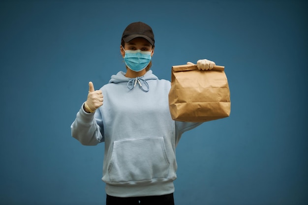 Courrier de fille dans un masque médical et des gants médicaux sur fond bleu