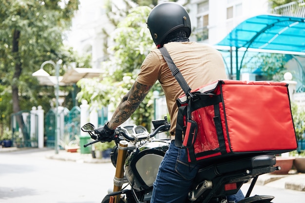 Courrier avec un grand sac thermique à moto lors de la livraison de nourriture aux clients