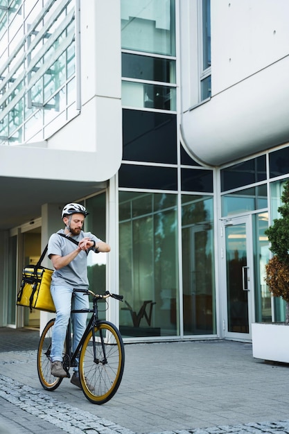 Courrier de livraison express avec sac isotherme regardant la montre à vélo